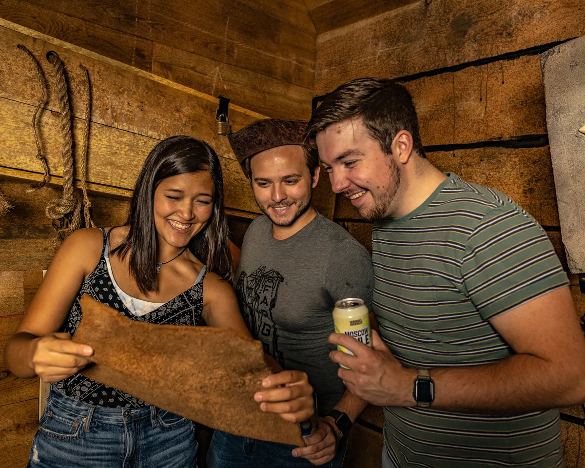 Three players comparing notes over a map during the Shipwrecked escape room at Labyrinth Nampa, Idaho.