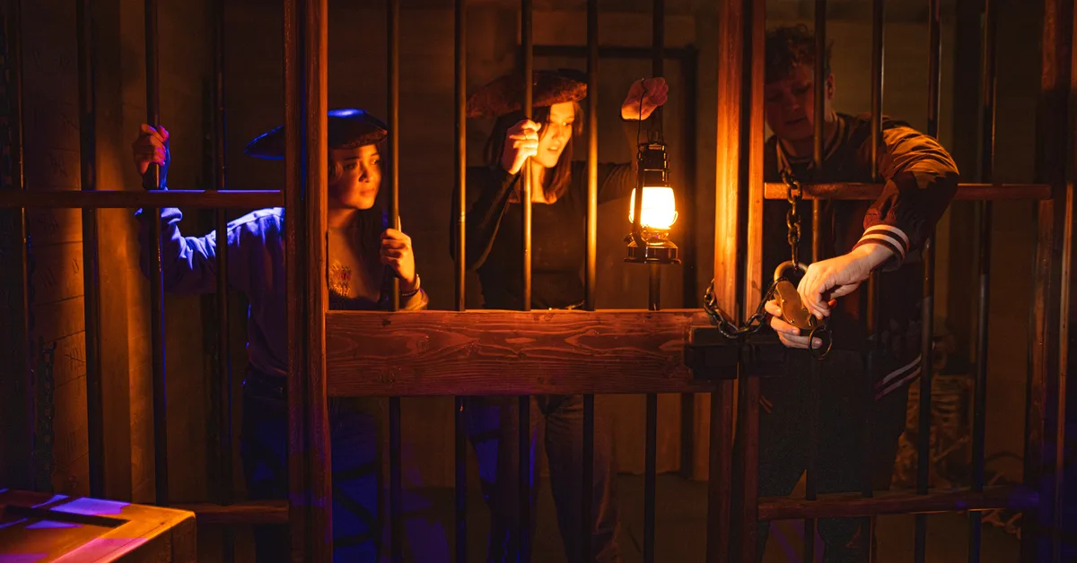 Players searching a pirate brig set by lantern light in the Dead Man's Chest escape room at Labyrinth in Boise, Idaho.