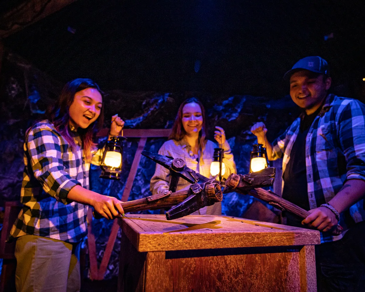 The Lost Mine escape room at Labyrinth in downtown Boise, three players placing crossed pickaxes by lantern light.