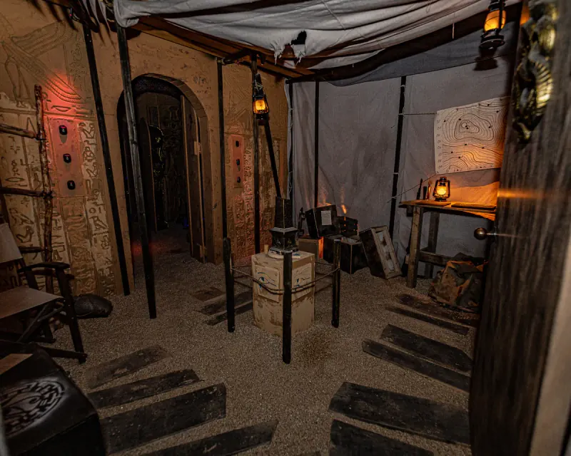 The expedition tent corner of Tomb of the Pharaohs Nampa, mortar and pestle on a crate and the Eye of Horus carved into the wall beyond