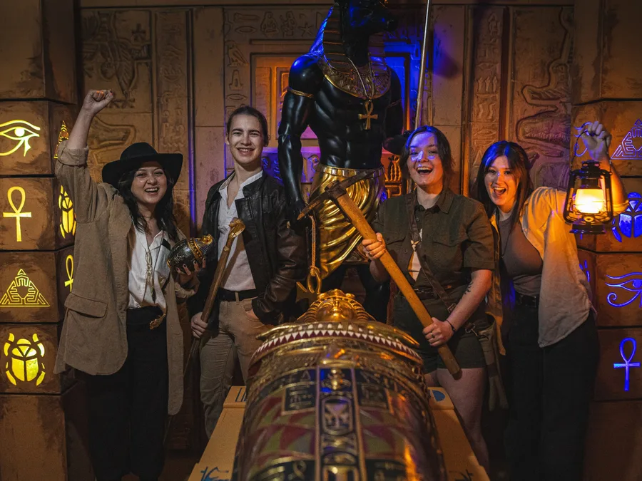 A party of four cheering around the gold sarcophagus in Tomb of the Pharaohs