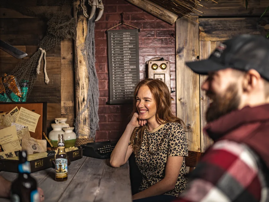 Two guests laughing over drinks at a table in the lounge